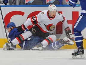 Connor Brown #28 of the Ottawa Senators forces Justin Holl #3 of the Toronto Maple Leafs to the ice at Scotiabank Arena on February 17, 2021 in Toronto, Ontario, Canada.