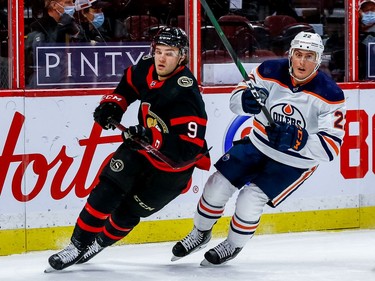 Senators centre Josh Norris and Oilers defenceman Tyson Barrie skate around the net during the first period.