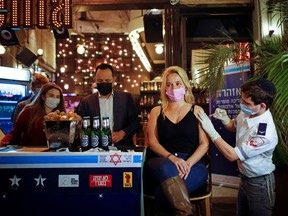 A woman receives a vaccination against COVID-19 as part of a Tel Aviv municipality initiative offering a free drink at a bar to residents getting the shot, in Tel Aviv, Israel February 18, 2021.