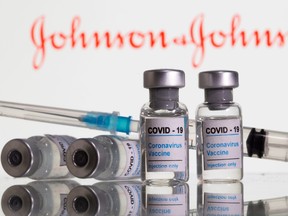 FILES: Vials labelled "COVID-19 Coronavirus Vaccine" and syringe are seen in front of displayed Johnson & Johnson logo in this illustration