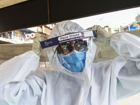 A health worker wears a Personal Protective Equipment (PPE) suit before collecting swab samples from people to test for the Covid-19 coronavirus, in Ahmedabad on February 22, 2021, as India's coronavirus cases passed 11 million. (Photo by SAM PANTHAKY / AFP)