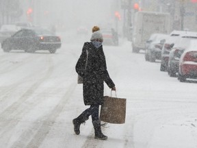 A pedestrian bundles up against the snow and COVID-19.