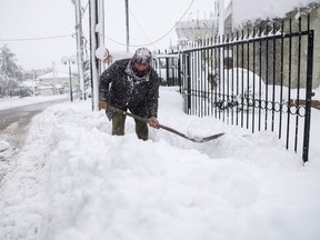 Panagiotis Economou shovels snow from the entrance of his property during heavy snowfall, in the village of Kapandriti, Greece, February 15, 2021.