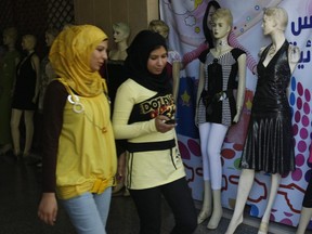 Palestinian Muslim women walk past a shop displaying western clothes for ladies in Gaza City, July 27, 2009.