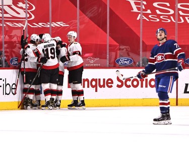 Senators players celebrate the first-period goal by defenceman Thomas Chabot (72) while the Canadiens' Jake Evans (71) looks at the videoboard.