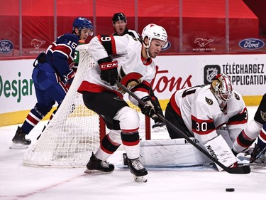 Senators centre Josh Norris clears the puck from the front of the crease guarded by netminder Matt Murray during the second period of Thursday's game against the Canadiens.