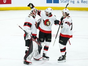 Senators goalie Marcus Hogberg receives congratulations from defencemen Christian Wolanin, middle, and Thomas Chabot after the Senators pulled out a 2-1 victory against the Jets in Winnipeg on Saturday.