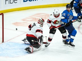 Senators goalie Marcus Hogberg watches the puck go over his shoulder as defenceman Christian Wolanin blocks out Jets forward Paul Stastny on a play in the first period of Saturday's game at Winnipeg.