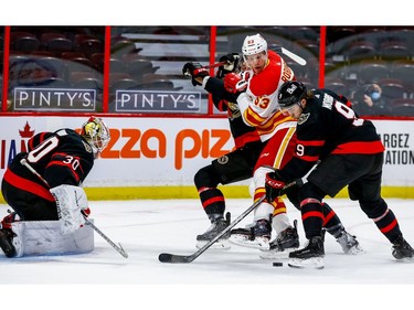 Ottawa Senators center Josh Norris (right) wins the puck battle against Calgary Flames right wing Buddy Robinson in front of goaltender Matt Murray during the second period on Thursday at the Canadian Tire Centre.