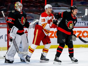 Ottawa Senators defenceman Thomas Chabot, without a stick, tries to check Calgary Flames left wing Matthew Tkachuk in front of goaltender Matt Murray during the second period on Thursday at The Canadian Tire Centre.