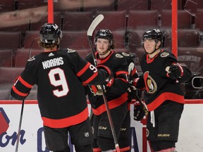 Drake Batherson, middle, is congratulated by teammates Josh Norris and Tim Stuetzle after scoring one of his two goals during Monday's game against the Flames at Canadian Tire Centre.