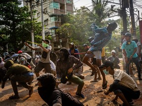 Anti-coup protesters use slingshots and pelt stones towards approaching security forces on March 28, 2021 in Yangon, Myanmar.