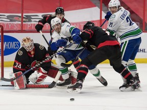 Vancouver Canucks centre Zack MacEwen is taken off the puck by Ottawa Senators defenceman Artem Zub during Monday's game.