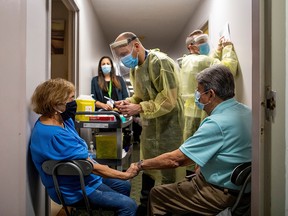 Married couple Teresa Salinas and Froilan Solis hold hands after being instructed by nurse Ruben Rodriguez from Humber River Hospital as they received their Pfizer/BioNTech COVID-19 vaccine at Caboto Terrace in Toronto March 11, 2021.