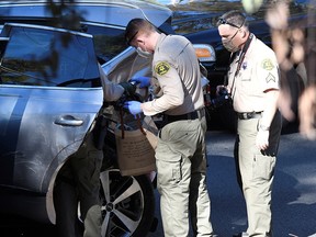 Los Angeles County Sheriff's Deputies inspect the vehicle of golfer Tiger Woods, who was rushed to hospital after suffering multiple injuries, after it was involved in a single-vehicle accident in Los Angeles February 23, 2021.