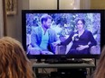 This photo illustration shows people wearing face masks, watch a televised conversation between Britain's Prince Harry with his wife Meghan Markle and US host Oprah Winfrey, in Arlington, Virginia March 7, 2021.