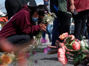 A woman prays during a vigil at a makeshift memorial outside the Gold Spa following the deadly shootings in Atlanta, Sunday, March 21, 2021.