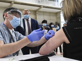 Ontario Premier Doug Ford, centre, watches Dr. Vitaly Bard administer the coronavirus vaccine to nurse Mary Glenen-Calder as he tours a mass COVID-19 vaccination clinic for Peel Region during the COVID-19 pandemic in Mississauga, Ont., on Monday, March 1, 2021.