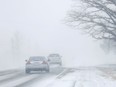 FILE: Motorists drive into a near-whiteout caused by snow blowing.