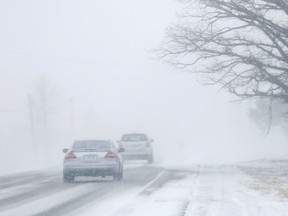 FILE: Motorists drive into a near-whiteout caused by snow blowing.
