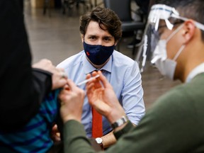 Prime Minister Justin Trudeau watches as someone gets vaccinated in Ottawa on March 30, 2021.