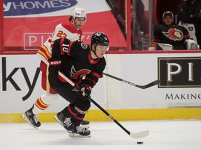 Ottawa Senators left wing Tim Stuetzle skates with the puck in front of Calgary Flames center Sean Monahan in the first period at the Canadian Tire Centre, March 22, 2021.