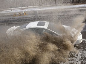 FILE: Cars splash through a deep puddle of melt water.