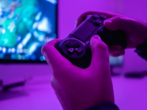 Closeup hands of anonymous male holding modern controller while playing a video game in a dark room.