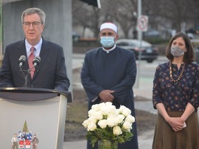 Mayor Jim Watson speaks at Thursday night's interfaith service in Marion Dewar Plaza to mark the anniversary of Ottawa's first COVID-19 death as Imam Samy Metwally of the Islamic Society of Gloucester and Dr. Vera Etches, medical officer of health, look on.