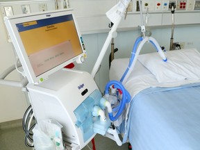 A ventilator stands next to a bed in an intensive care unit.