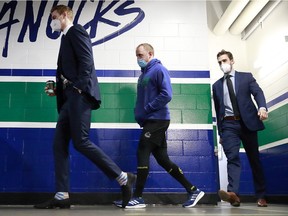 Tyler Myers, Nate Schmidt and Brandon Sutter of the Vancouver Canucks walk to the Canucks dressing room before their NHL game against the Calgary Flames at Rogers Arena on Wednesday. Myers and Sutter have been placed on the NHL's COVID-19 protocol list.