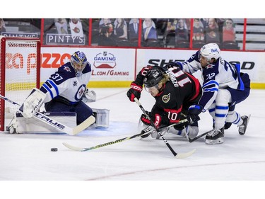 Ottawa Senators left wing Ryan Dzingel (middle) gets hauled down by Winnipeg Jets centre Mason Appleton (right) in front of Winnipeg Jets goaltender Connor Hellebuyck during first period NHL action at the Canadian Tire Centre.