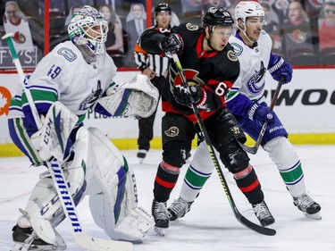 Ottawa Senators right wing Evgenii Dadonov (63) battles with Vancouver Canucks defenceman Travis Hamonic (27) in front of goaltender Braden Holtby (49) at the Canadian Tire Centre on Monday.