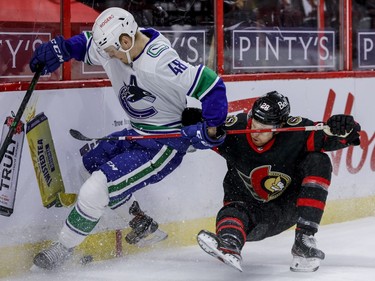 Ottawa Senators right wing Connor Brown (28) goes awkwardly into the end boards while battling for a loose puck with Vancouver Canucks defenceman Olli Juolevi (48) during first period NHL action at the Canadian Tire Centre.