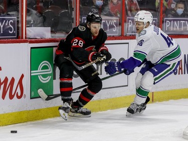 Ottawa Senators right wing Connor Brown (28) battles for a loose puck with Vancouver Canucks defenceman Olli Juolevi (48) during first period NHL action at the Canadian Tire Centre.