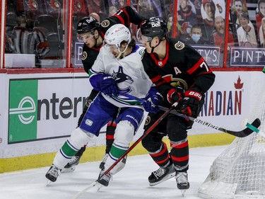 Ottawa Senators right wing Drake Batherson (19) and left wing Brady Tkachuk (7) check Vancouver Canucks defenceman Quinn Hughes (43) during first period NHL action at the Canadian Tire Centre on Monday.