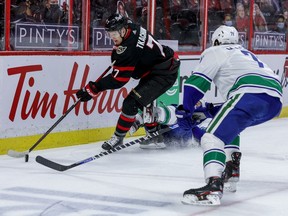 Ottawa Senators left wing Brady Tkachuk (7) flattens Vancouver Canucks center Brandon Sutter (20) and controls the puck against center Zack MacEwen (71) during first period NHL action at the Canadian Tire Centre on WQednesday.