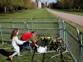Children lay flowers on the Long Walk in front of Windsor Castle, after Britain's Prince Philip, husband of Queen Elizabeth, died at the age of 99, in Windsor, near London, England, Thursday, April 15, 2021.