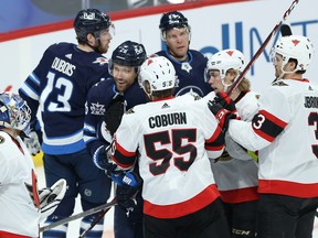 Winnipeg Jets captain Blake Wheeler (centre) draws plenty of attention as he tries to speak with Ottawa Senators goaltender Anton Forsberg, who was still wearing his Jets mask, in Winnipeg on Monday.