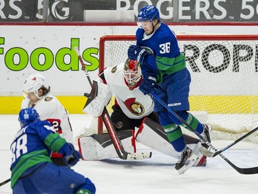 Ottawa Senators goalie Marcus Hogberg (1) makes a save on Vancouver Canucks defenseman Nate Schmidt (88) as  forward Nils Hoglander (36) looks for the rebound  in the third period at Rogers Arena. Canucks won 4-2.