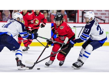 Ottawa Senators left wing Tim Stuetzle (18) splits between the checks of Winnipeg Jets defenceman Neal Pionk (4) and left wing Nikolaj Ehlers.