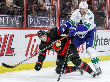 Ottawa Senators right wing Drake Batherson (19) gets knocked to the ice by Vancouver Canucks defenceman Tyler Myers.
