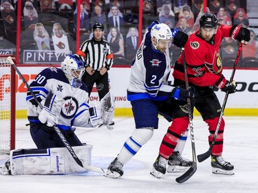 Ottawa Senators centre Colin White (36) battles with Winnipeg Jets defenceman Dylan DeMelo (2) as goaltender Laurent Brossoit (30) makes a save.