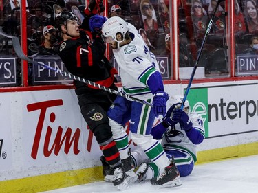 Ottawa Senators left wing Brady Tkachuk (7) flattens Vancouver Canucks centre Brandon Sutter (20) and gets checked by centre Zack MacEwen (71) during the first period.