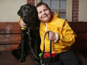 Ollie Acosta-Pickering, 8, and his "Buddy dog" Hope pose for a photo at their home on Wednesday.