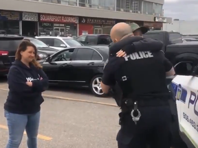 Peel Regional Police Sgt. Paul Brown hugs protesters outside of a Mississauga gym without wearing PPE on Friday, April 16, 2021.