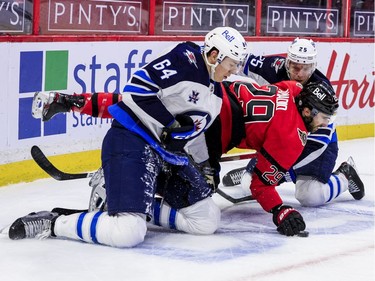 Ottawa Senators centre Michael Amadio (29) plays the puck with his glove as he is checked by Winnipeg Jets defenceman Logan Stanley (64) and centre Paul Stastny.