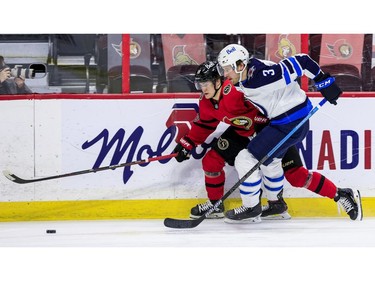 Ottawa Senators left wing Tim Stuetzle (18) tries to get past the check of Winnipeg Jets defenceman Tucker Poolman.