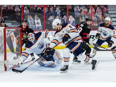 Edmonton Oilers defenceman Adam Larsson (6) clears the puck as goaltender Mikko Koskinen (19) dives across the crease as Ottawa Senators left wing Brady Tkachuk (7) and right wing Connor Brown (28) follow the play.