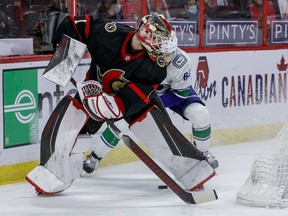 Ottawa Senators goaltender Marcus Hogberg loses a puck battle behind his net with Vancouver Canucks centre Tyler Motte, April 28, 2021.